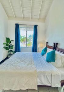 een slaapkamer met een groot bed met blauwe kussens bij Palm JA SCA31 - Relaxing 1 BR with Beach & Pool Access in Montego Bay