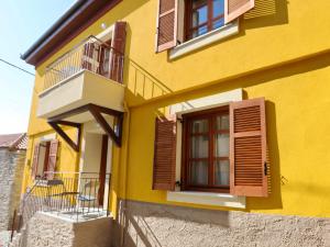 Edificio amarillo con persianas marrones y balcón en Kallichoron 2, en Kavala