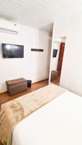Pousada Mima في غرامادو: غرفة نوم بيضاء مع سرير وأريكة