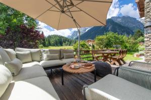 une terrasse avec un canapé et une table avec un parasol dans l'établissement Chalet Cinq Moutons, à Orsières