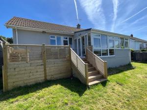 a house with a wooden fence in the yard at Bright Bungalow with 3 bedrooms and Garden in Porthlevan in Porthleven