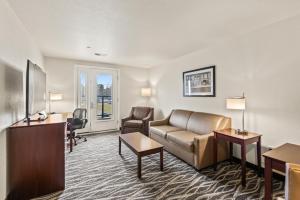 a hotel room with a couch and a desk at Riverstone Suites by Cobblestone Hotels - Chippewa Falls in Chippewa Falls