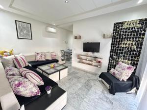 uma sala de estar com um sofá e uma televisão em Appartement haut standing a sousse em La Corniche