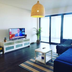 uma sala de estar com um sofá azul e uma televisão em luxury Plazza Sea view em Costa da Caparica