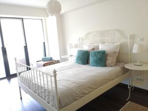 um quarto branco com uma cama branca com almofadas azuis em luxury Plazza Sea view em Costa da Caparica
