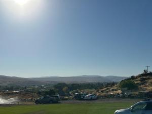 a group of cars parked in a field with mountains in the background at Infidel Acres Motorcycle Campground in Naches