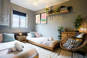 uma sala de estar com duas camas e uma cadeira em Cheltenham 3 Bedroom Cottage-Neon Wonderland-Town Centre-Parking-Sleeps 6 