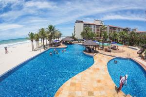 un complejo con piscina junto a una playa con palmeras en Belíssimo Apartamento no resort do Beach Park - By Ideal Trip Hospedagens, en Aquiraz