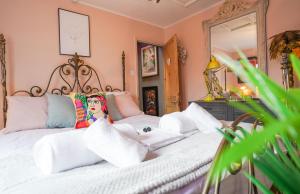 Schlafzimmer mit einem weißen Bett und einem großen Spiegel in der Unterkunft Cheltenham 3 Bedroom Cottage-Neon Wonderland-Town Centre-Parking-Sleeps 6 