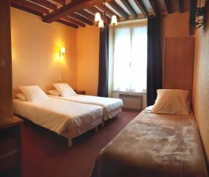 a hotel room with two beds and a window at Le Mogador in Bayeux