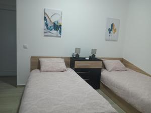 two beds in a room with a desk and aermottermottermott at ApHEARTments in Gevgelija