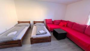 ein Wohnzimmer mit 2 Betten und einem roten Sofa in der Unterkunft Apartmánový dom Most pri Bratislave in Senec