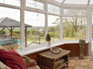 a living room with large windows and a table at Green Haven Pembrokeshire in Pembrokeshire