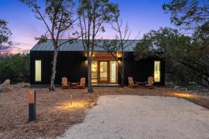 mały czarny dom z dwoma krzesłami i drzewami w obiekcie The Cedars Ranch w mieście Wimberley