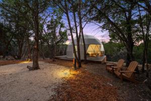 a dome tent in the woods with benches and lights at The Cedars Ranch in Wimberley