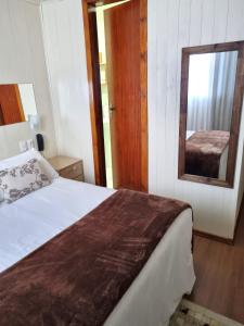 um quarto com uma cama grande e um espelho em Pousada Mima em Gramado