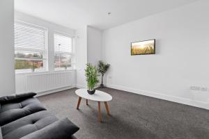 een woonkamer met een bank en een tafel bij Perfectly Located 2-Bed w/ Free Private Parking in Peterborough