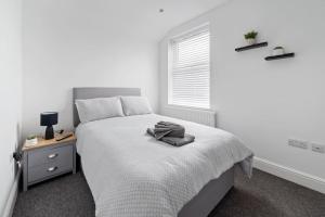 een witte slaapkamer met een bed en een raam bij Perfectly Located 2-Bed w/ Free Private Parking in Peterborough