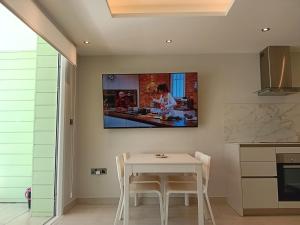 een keuken met een tafel en een tv aan de muur bij Marina Club Adriatic Gibraltar - Studio Apartment in Gibraltar
