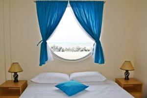 1 dormitorio con 1 cama con cortinas azules y ventana en Hotel Crucero, en Cojimíes