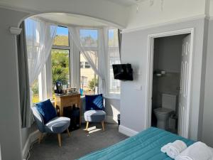 a bedroom with a bed and two chairs and a window at Bentley Lodge in Torquay