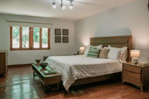 a bedroom with a bed and a table and two windows at Hacienda La Perezosa en Cerro Azul in Cerro Azul