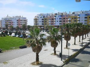 una fila di palme in un parco con edifici di Caparica ap vista mar a Costa da Caparica