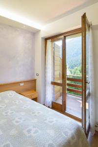 a bedroom with a bed and a large window at Hotel Diana in Auronzo di Cadore
