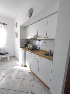 una cocina con armarios blancos y fregadero en Apartment Jelas en Živogošće