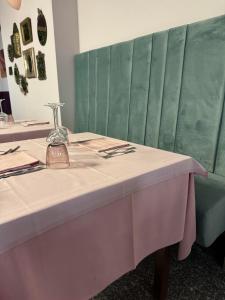 una mesa con mantel rosa y un banco verde en Da Noi Trattoria Hotel, en Vergato