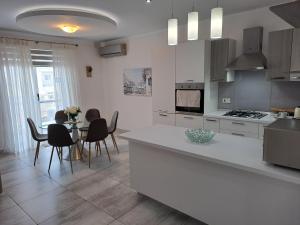 eine Küche mit einem Tisch und Stühlen sowie eine Küche mit weißen Schränken in der Unterkunft 74 temple point 3 bedroom APT in Marsaxlokk