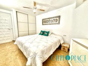 um quarto com uma cama branca e uma ventoinha de tecto em Delfín a 100 metros de la playa em Calpe