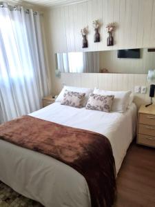 um quarto com uma grande cama branca e 2 almofadas em Pousada Mima em Gramado