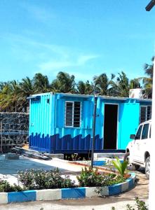 ein blaues Haus mit einem weißen Truck, der davor parkt. in der Unterkunft Chan Beach Resort & Hotel in Bahūr