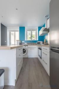 - une cuisine avec des placards blancs et des murs bleus dans l'établissement Appartement au cœur de Cancale, à Cancale