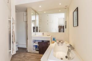 La salle de bains est pourvue d'une grande baignoire blanche et d'un lavabo. dans l'établissement Appartement vue sur la baie de St Briac, à Saint-Briac-sur-Mer