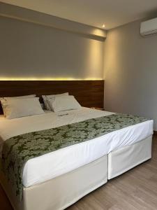 een slaapkamer met een groot wit bed met een houten hoofdeinde bij Vista Azul Apart Hotel - Vista Pedra Azul in Domingos Martins