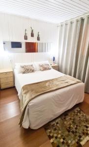 um quarto com uma grande cama branca com cortinas em Pousada Mima em Gramado