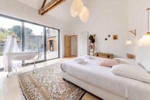 a white bedroom with a bed and a large window at La Familia - Maison chaleureuse in Laval