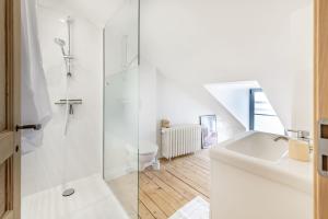 uma casa de banho branca com um chuveiro e um lavatório. em La Familia - Maison chaleureuse em Laval