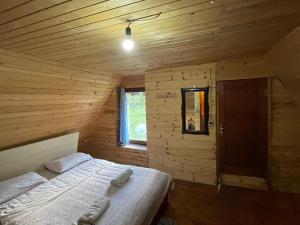 1 dormitorio con 1 cama en una cabaña de madera en bujtina 2, en Valbonë