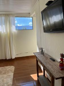 a living room with a television and a wooden table at Pouso de Teria in Tiradentes