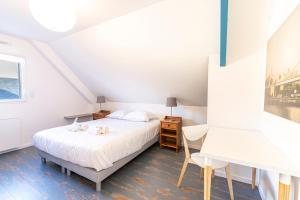 ein weißes Schlafzimmer mit einem Bett und einem Schreibtisch in der Unterkunft Pavillon d'Emeraude in Saint-Lunaire