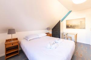 Schlafzimmer mit einem Bett mit weißer Bettwäsche und einem Tisch in der Unterkunft Pavillon d'Emeraude in Saint-Lunaire