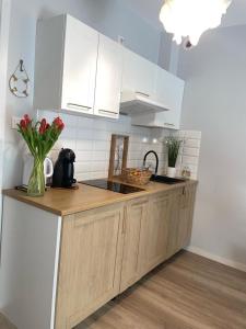 a kitchen with white cabinets and a vase of flowers at Apartamenty Przy Wydmie in Rowy