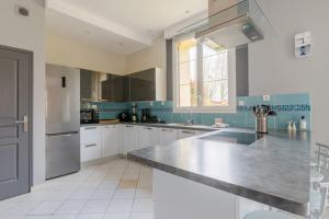 a kitchen with white cabinets and a stainless steel counter top at Paisible maison dans un cadre verdoyant in Pleurtuit
