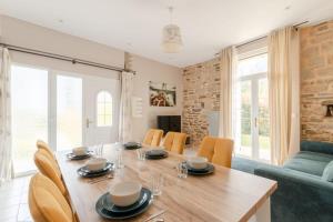 a dining room and living room with a wooden table and chairs at Paisible maison dans un cadre verdoyant in Pleurtuit