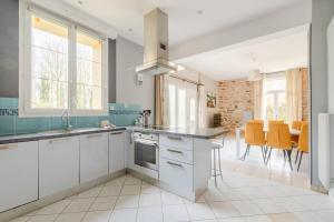 a kitchen with white cabinets and orange chairs at Paisible maison dans un cadre verdoyant in Pleurtuit