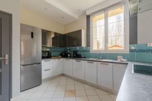 a kitchen with white cabinets and a stainless steel refrigerator at Paisible maison dans un cadre verdoyant in Pleurtuit