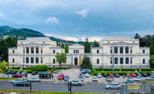 a large white building with cars parked in a parking lot at Apartments Museum in Sarajevo